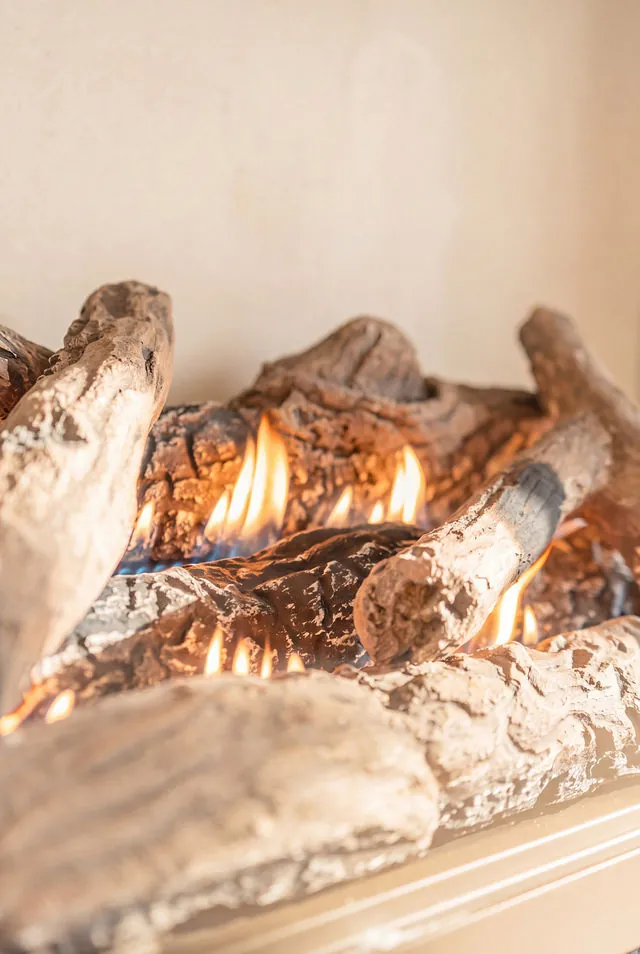 Close product detail of ceramic logs and flames inside a fireplace