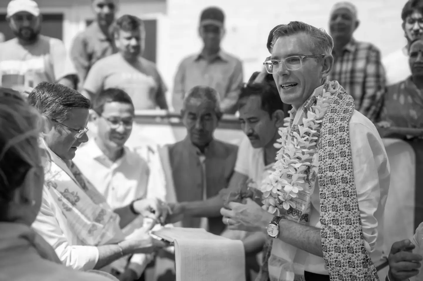 Documentary photo of an official welcomed with a garland at a community event