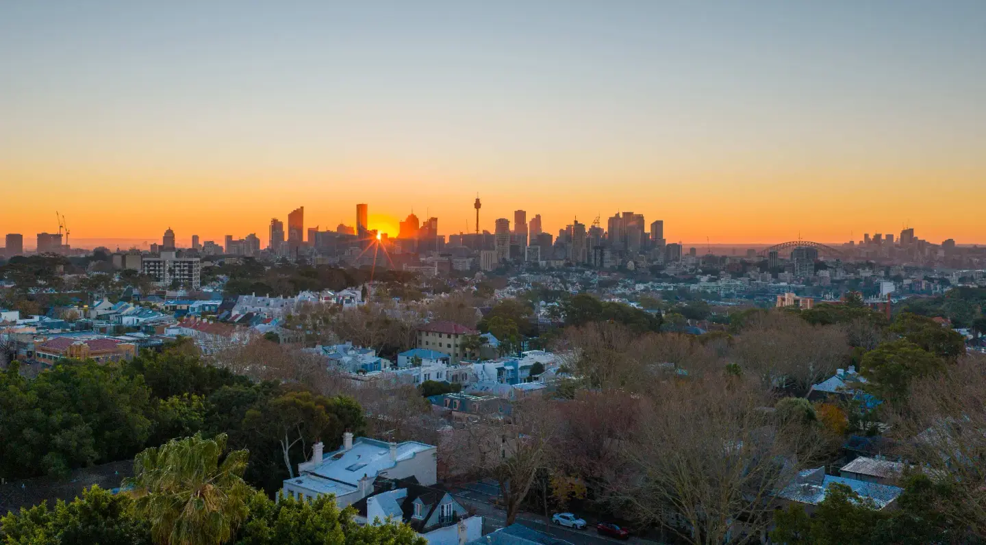 Drone aerial over Sydney's eastern suburbs at sunrise, city skyline on the horizon